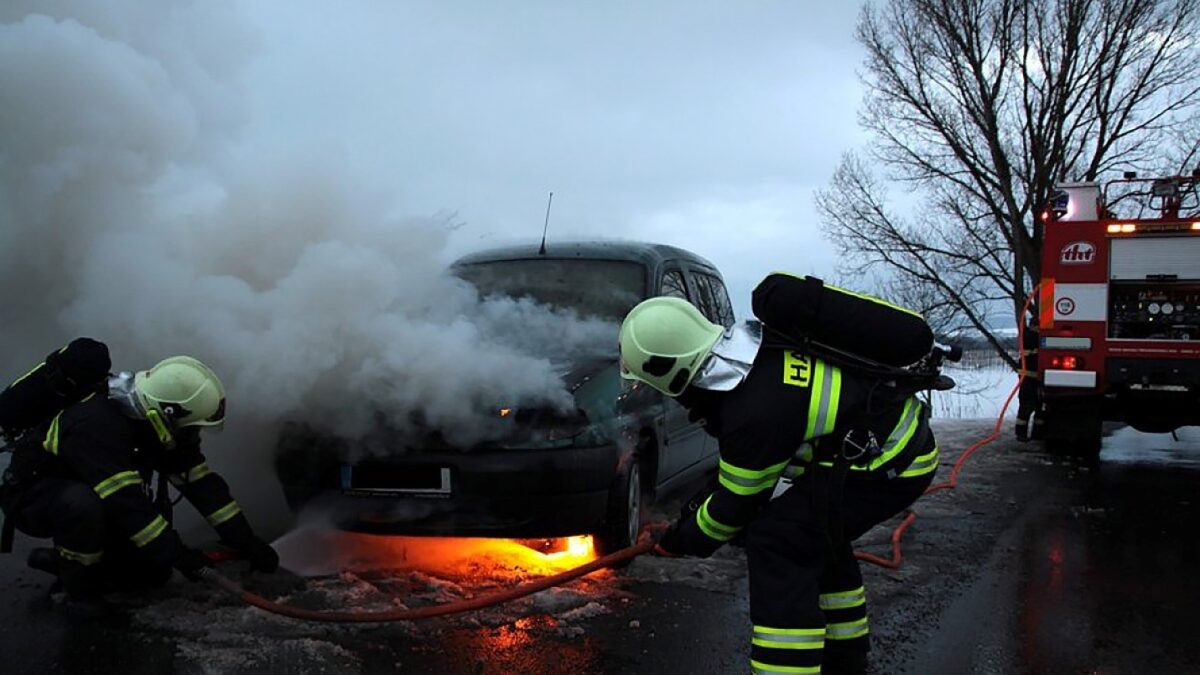A car on fire being distinguished by firemen