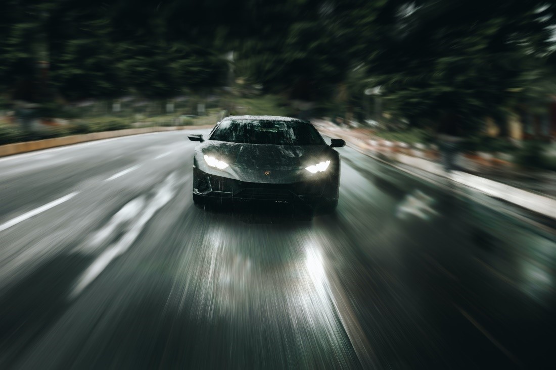 A grey luxury car speeding on a road