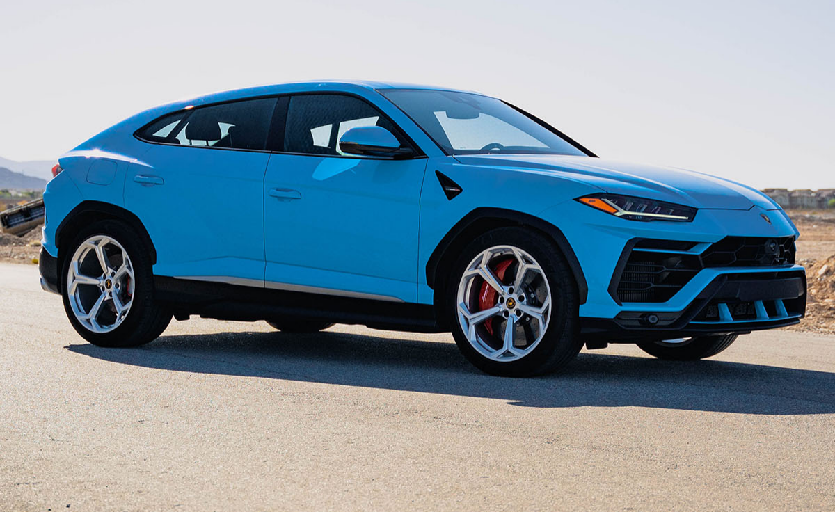 The Lamborghini Urus in blue is parked on a road.